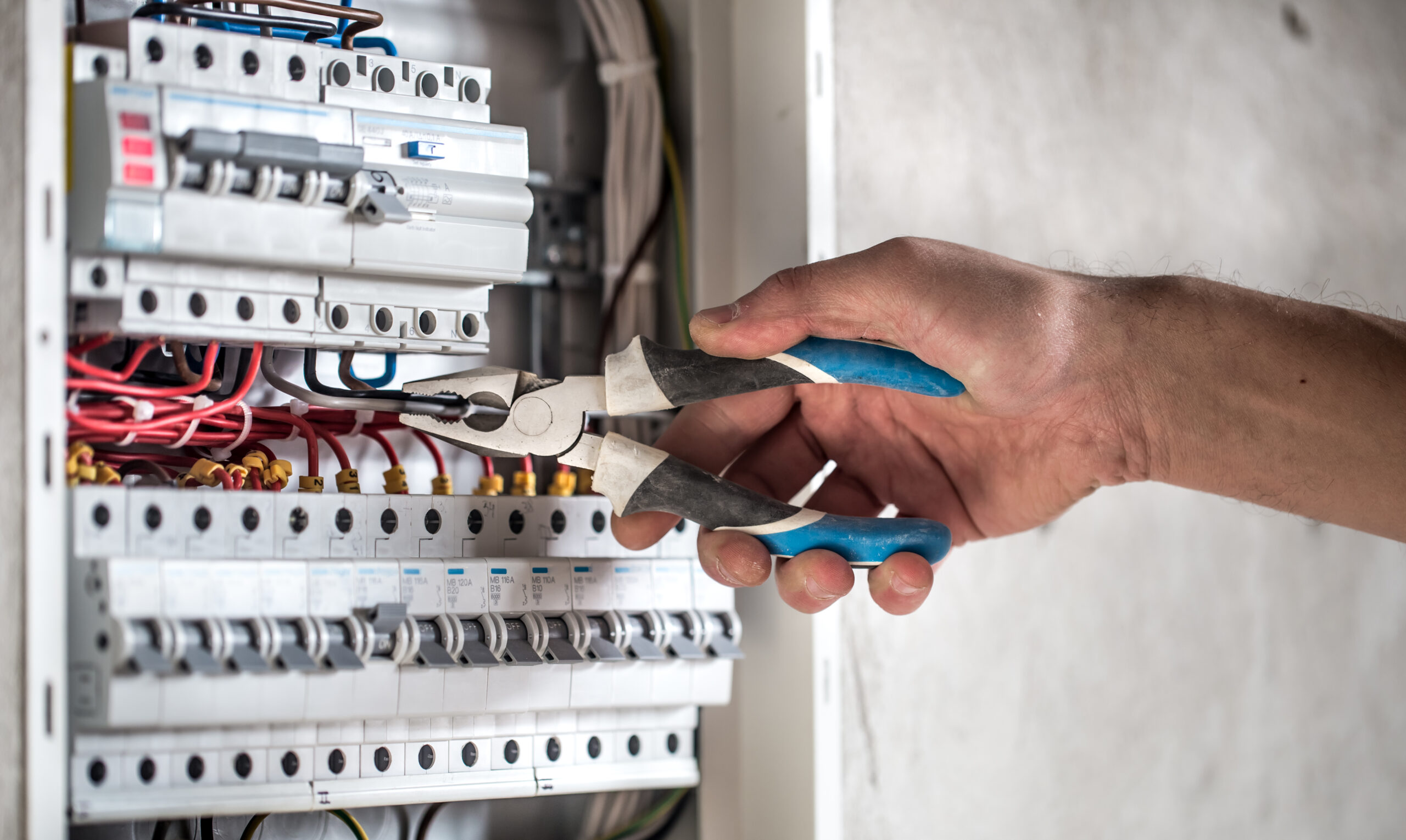 Man, an electrical technician working in a switchboard with fuses. Installation and connection of electrical equipment. Close up.